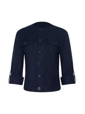The Anouk Jean Jacket is a dark blue, collarless denim jacket featuring a relaxed fit, button-up front, long sleeves, rolled cuffs, and two chest pockets with flaps.