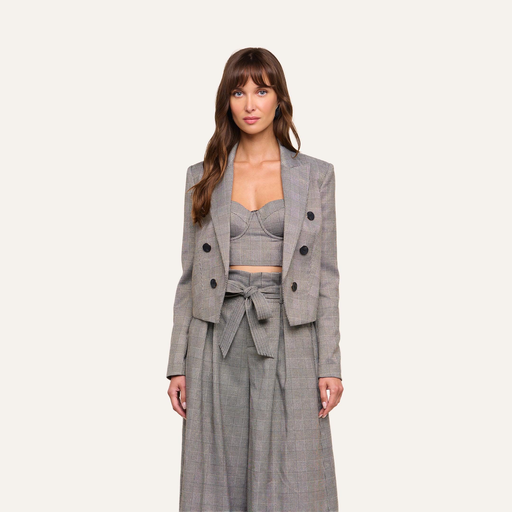 A woman stands facing forward, wearing the Lila Tweed Blazer styled with a crop top and high-waisted wide-leg pants featuring a bow tie at the waist, set against a plain light background.
