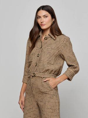 A woman wears the Jia Cropped Tweed Jacket in textured tan with matching high-waisted pants, standing with one hand in her pocket against a plain light gray background.