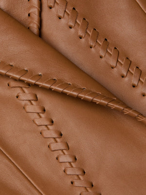 Close-up of brown leather on the Dulcie Leather Blazer, featuring decorative whipstitch crisscross details that highlight its premium texture and expert craftsmanship.