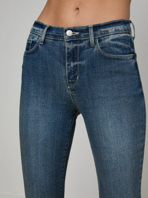 A close-up of a person’s midsection wearing the Sada Cropped Slim-Leg Jean, featuring blue stretch denim, a button closure, belt loops, and subtle fading on the thighs.