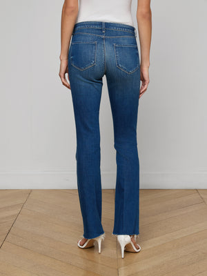 A person stands on a wooden floor with their back to the camera, wearing Sneeki Low-Rise Straight-Leg Jeans with frayed hems and visible back pockets, styled with white high-heeled shoes.