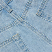 Close-up of the Teya Low-Rise Jean Short in a light blue wash, showcasing overlapping seams, pockets, and visible stitching details. The image highlights the texture, color, and structure of the denim material.