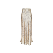 The Ryker Silk Maxi Skirt, a long, high-waisted cream satin piece adorned with a delicate floral pattern, embodies minimalist sophistication and is displayed on a plain white background.