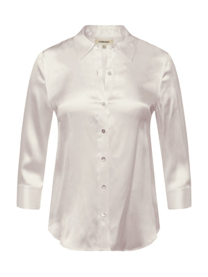 The Dani Silk Blouse is a light pink, long-sleeve button-down with a pointed collar and slightly curved hem, shown on a white background.
