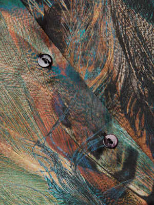 Close-up of the L'AGENCE Tyler Silk Blouse: features vibrant green, orange, and brown abstract feather prints on silk fabric with two black buttons sewn along the seam.