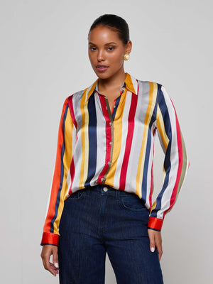A woman in the Tyler Silk Blouse by L'AGENCE, featuring multi-colored stripes and a button-down design.