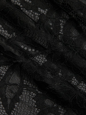 Close-up of delicate black lace fabric with an intricate floral pattern and textured leaf designs, featured on the Rhett Oversized Lace Blouse. Ideal for adding elegance to any outfit or as a statement piece in your wardrobe.