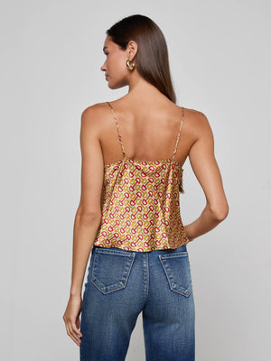 A woman with long brown hair, shown from the back against a plain gray background, wears L’AGENCE’s Calista Silk Camisole in a gold and pink horse bit print with blue jeans.