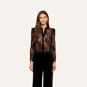 A woman stands facing forward, wearing the Dorothea Velvet Lace Blouse with long sleeves and Chantilly lace details, paired with black pants. She is set against a plain light background.