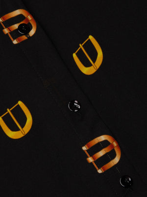 Close-up of the L'AGENCE Nina Silk Blouse, a relaxed fit black shirt with black buttons and a bold yellow-orange buckle print along the button placket.