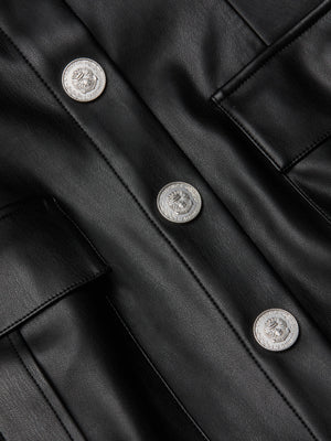 Close-up of the L'AGENCE Midy Vegan Leather Dress, a black mini with a structured fit, three crest-embossed silver buttons, and two flap pockets.