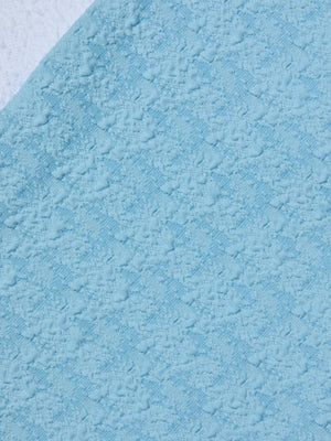 Close-up of the Vanessa High-Waisted Bikini Bottom in light blue, featuring a textured, bouclé-like fabric placed over white—both displaying a soft, fluffy swimwear surface.