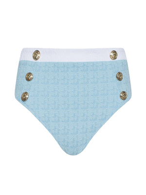 The Vanessa High-Waisted Bikini Bottom features light blue bouclé swim fabric with a subtle houndstooth pattern, white waistband, and decorative gold buttons for a stylish look and moderate coverage.