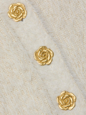Three gold rose-shaped embellishments are arranged diagonally on the soft, off-white fuzzy knit of the Talulla Cardigan by L'AGENCE, featuring a subtle striped pattern and a cozy, stylish look.