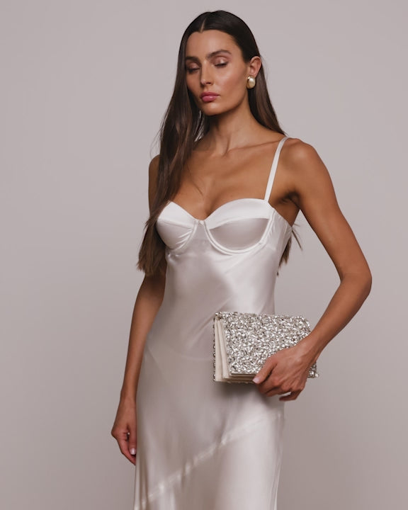 White and Silver embellished clutch bag with stones being held by model wearing a white dress.